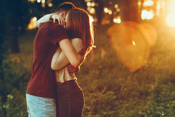 Portrait of a charming young couple embracing against sunrise while dating in the morning.