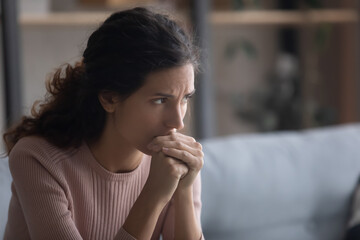 Close up upset face of young Latina woman deep in sad thoughts. 30s female looks aside feels unhappy goes through divorce, unplanned pregnancy and abortion decision, life troubles and problems concept