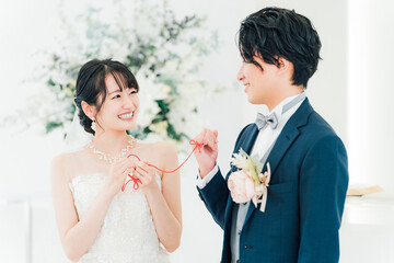 結婚式場で赤い糸で結ばれる新郎新婦（ブライダル・ウェディング）
                        