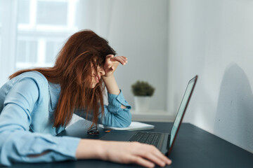 woman in blue shirt in front of laptop fatigue depression work