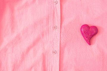 A magenta heart on a pink shirt. Minimal surreal concept for Valentine day banner or card. Design for clothes advertisement. Flat lay