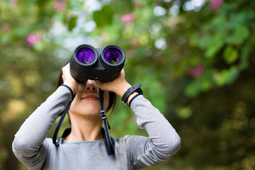 Woman looking though binocular in jungle