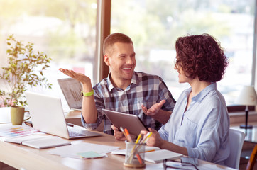 Positive  smiling colleagues talking at the table     