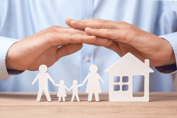 Family insurance and home. Man in  shirt covers his family with his father, mother, son and daughter and the house.