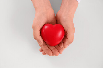Human hands holding a red heart, health care and medical support, love and compassion, isolated on a white background