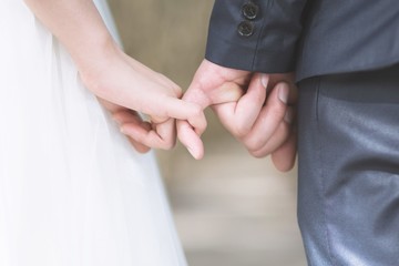 Loving Young love married couple holding hands and stand together in ceremony wedding day marry scene. Young love couple be hand in hand pinky promise  or pinky swear.