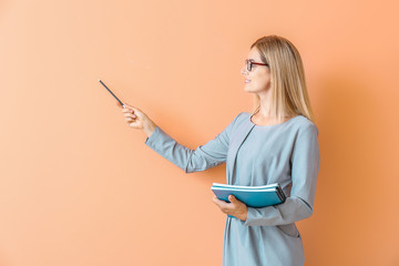 Beautiful female teacher showing something on color background