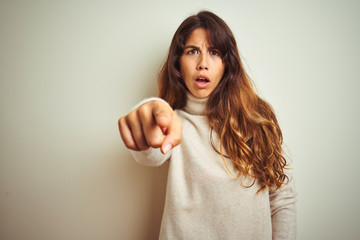 Young beautiful woman wearing winter sweater standing over white isolated background pointing displeased and frustrated to the camera, angry and furious with you