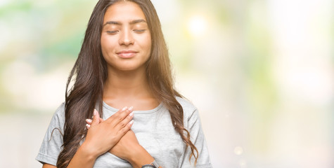 Young beautiful arab woman over isolated background smiling with hands on chest with closed eyes and grateful gesture on face. Health concept.