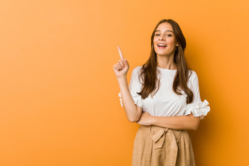 Young caucasian woman smiling cheerfully pointing with forefinger away.
