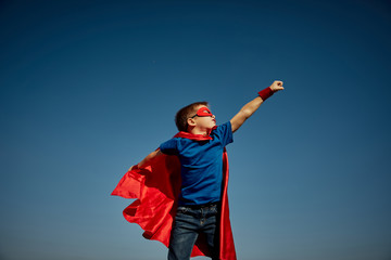 Super hero child (boy) against blue sky