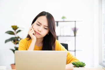 Asian young woman seriously working on computer laptop in house. She thinking find solution problem of work